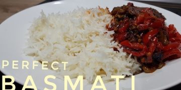 Plate of perfectly fluffy white basmati rice next to a rich, chunky curry with red peppers, lentils, and dark sauce