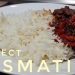 Plate of perfectly fluffy white basmati rice next to a rich, chunky curry with red peppers, lentils, and dark sauce