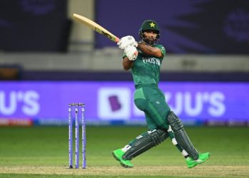 Fakhar Zaman of Pakistan batting in a cricket match, playing a powerful shot with stumps visible behind him on a stadium field.