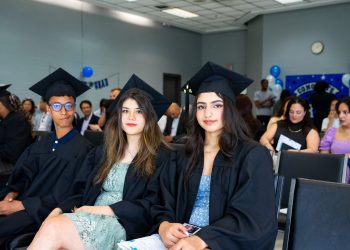 University graduates wearing caps and gowns seated at a graduation ceremony