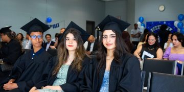 University graduates wearing caps and gowns seated at a graduation ceremony