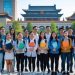 Group of international students holding books and folders while standing on a university campus in China with traditional Chinese architecture in the background.