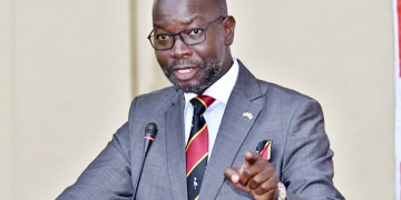 "Hon. Denis Hamson Obua, Government Chief Whip, speaking at a public event in Uganda"