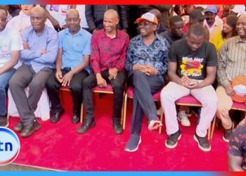 Kenyan political leaders seated together at a Linda Mwananchi rally event with supporters in the background
