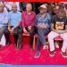Kenyan political leaders seated together at a Linda Mwananchi rally event with supporters in the background