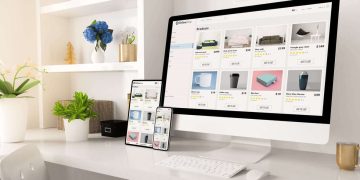 Modern home office desk with computer, tablet and smartphone showing an online store with small business products.