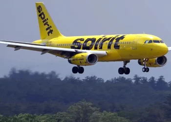 Spirit Airlines airplane in bright yellow livery descending for landing with landing gear deployed