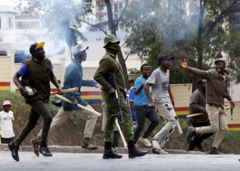 Kenya goonism – protesters and a police officer clash on the streets amid tear gas and political unrest in Kenya
