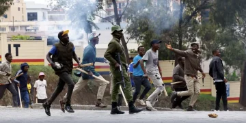 Kenya goonism – protesters and a police officer clash on the streets amid tear gas and political unrest in Kenya