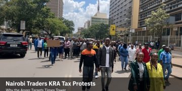 Nairobi traders marching in a street protest against KRA tax policies near high-rise buildings and police barriers