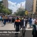 Nairobi traders marching in a street protest against KRA tax policies near high-rise buildings and police barriers